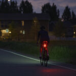 A rear bike light shines brightly in the evening