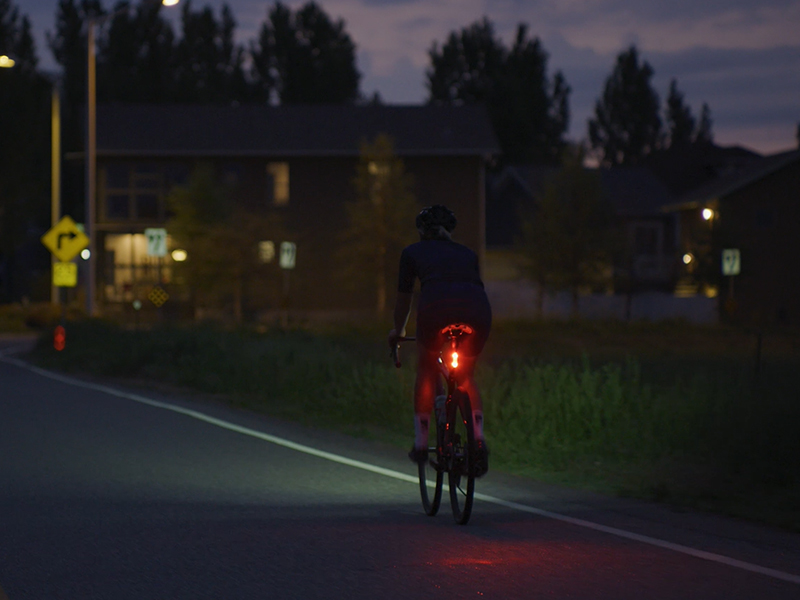 A rear bike light shines brightly in the evening